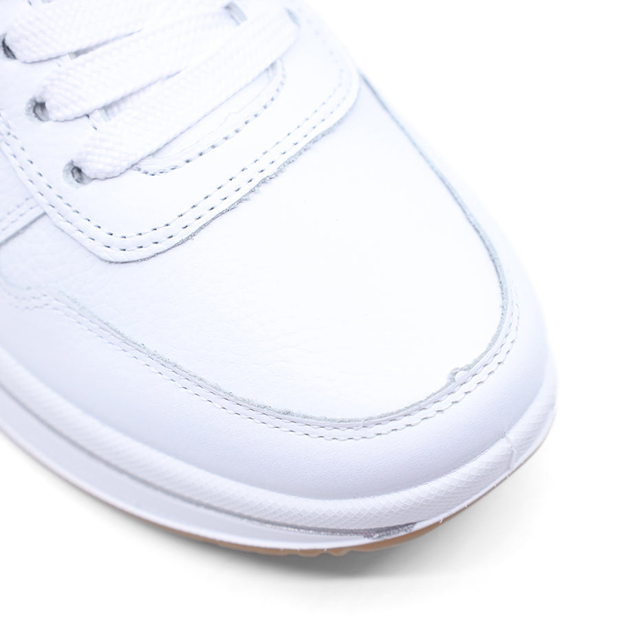 White sneaker with a grey and yellow patch on a white background