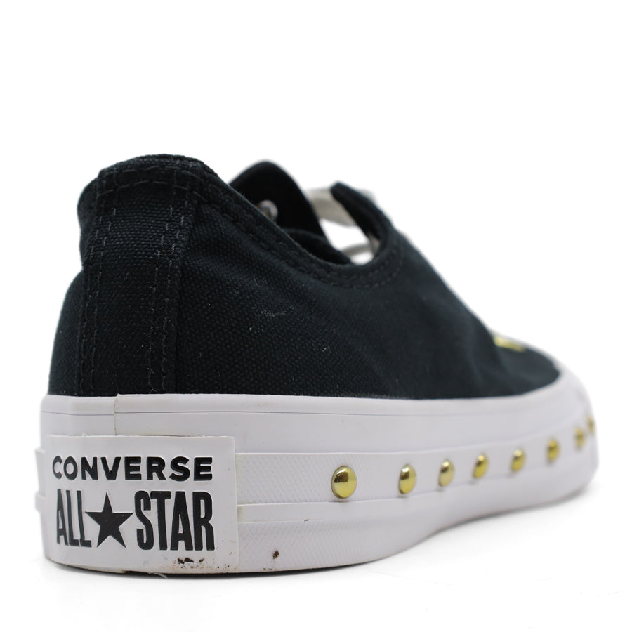 back view of black lace up sneaker with gold stud details along the white sole